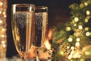 Two glasses with champagne on a wooden table near a Christmas tree during tours, things to do in Independence MO